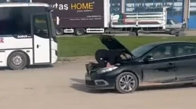 Seyir halindeki otomobilin motoruna oturdu, arızayı bulmaya çalıştı
